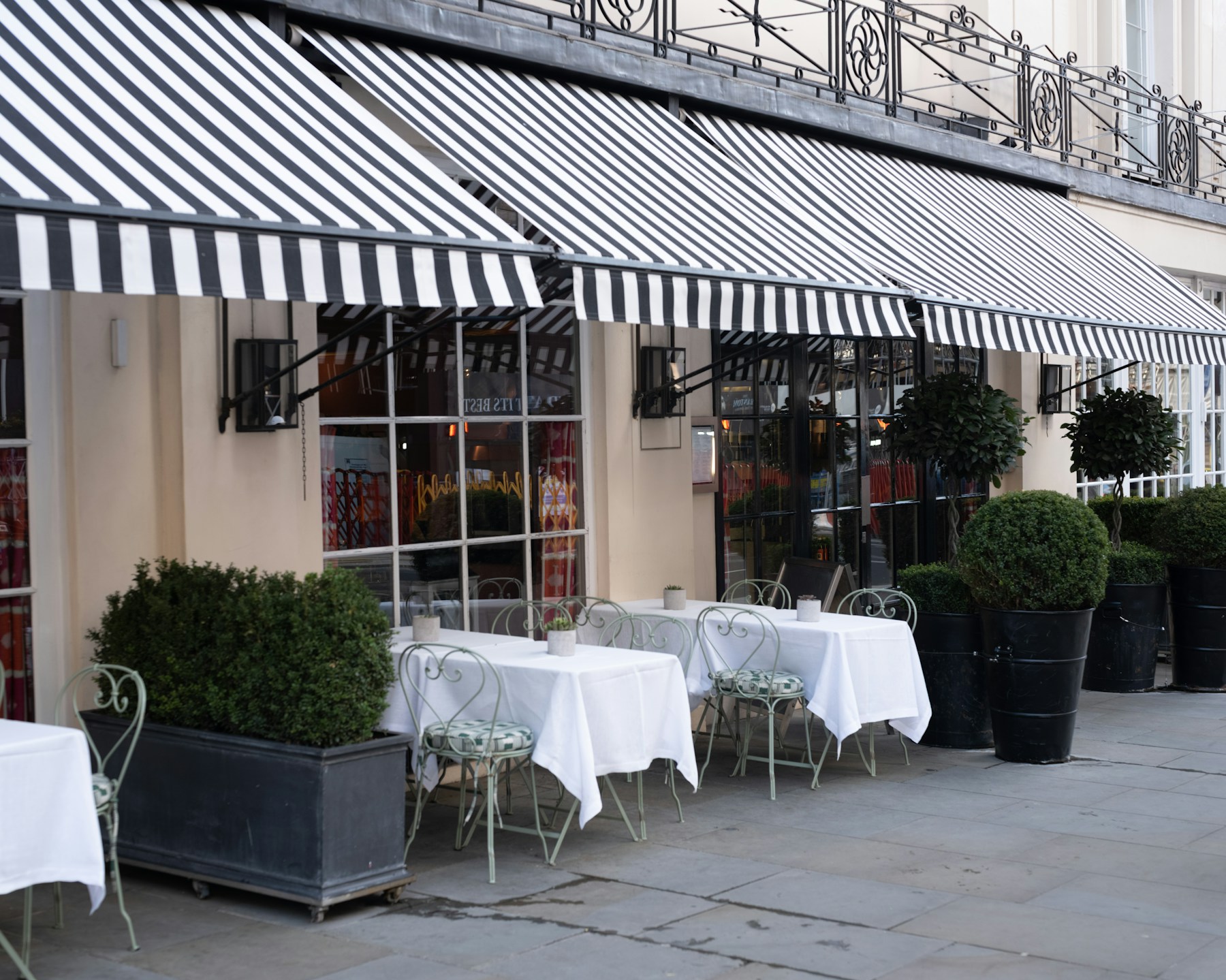 Terasa restorana s prugastim tendama i postavljenim stolovima